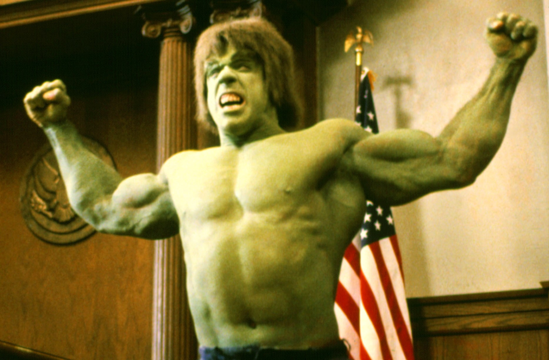 Hulk flexes in a court room in front of the American flag in The Trial of the Incredible Hulk